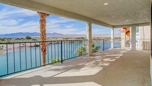 A covered outdoor area with a pool, a palm tree, and a view of mountains. - Best Luxury Riverfront Home w/ Private Pool & Dock (Bullhead City)