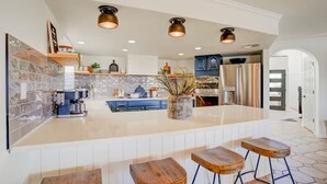 A modern kitchen with a central island, bar stools, and pendant lighting. - Best Luxury Riverfront Home w/ Private Pool & Dock (Bullhead City)