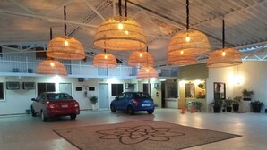 Un vestíbulo amplio con un gran carpeta floral, lámparas colgantes de ratán y coches aparcados.