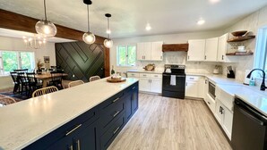 Una cocina moderna con una isla grande, armarios oscuros y una pared decorativa con motivo de espiga.