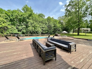 A wooden deck with lounge chairs and a pool.