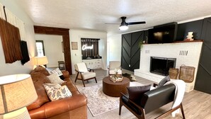 Una sala de estar con chimenea, sofás de cuero, una mesa de centro y un televisor montado en la pared.