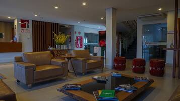 Una hall d'hotel moderna con divani in pelle, un tavolino con riviste e una reception.