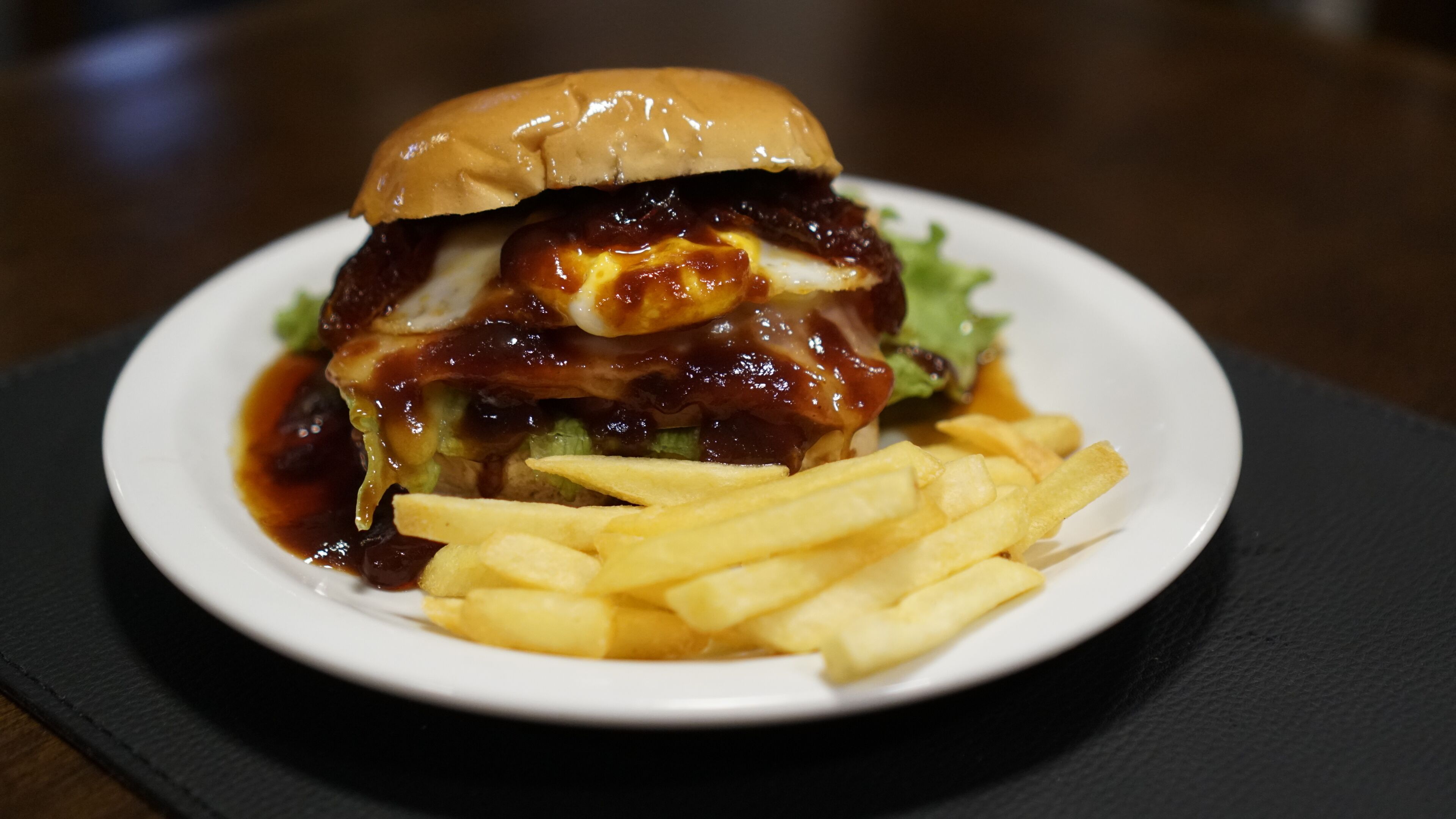 A burger with fries on a white plate.