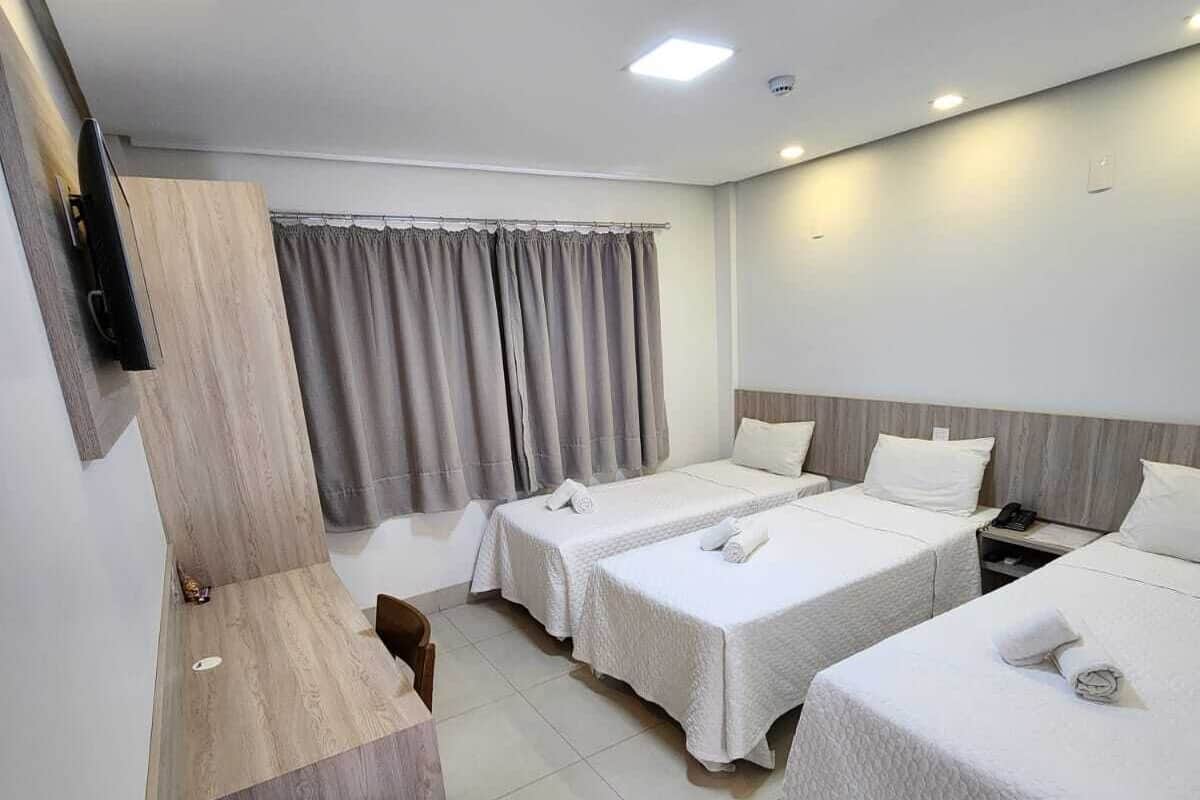 A hotel room with two beds, a desk, and a TV.