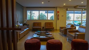Zona d'espera moderna amb seients de pell, una taula de cafè amb revistes i grans finestres que donen vista a l'exterior.