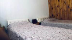 Ein Zimmer mit zwei Betten, einem Holzschrank und einer weißen Wand.