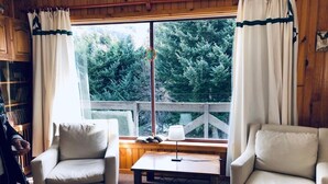 Ein gemütliches Zimmer mit zwei Sesseln, einem kleinen Tisch und einem Fenster mit Vorhängen.