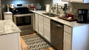 Una cocina moderna con armarios blancos, electrodomésticos de acero inoxidable y una alfombra estampada.