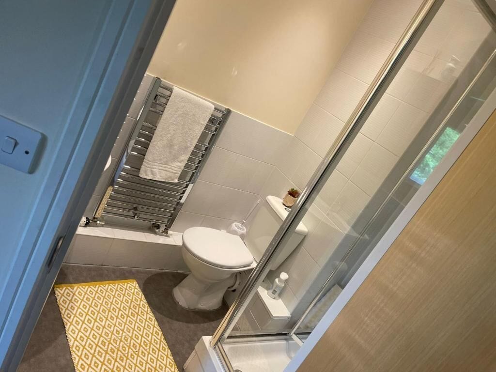A bathroom with a toilet, a shower, and a towel rack.