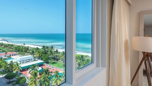 Habitación de hotel con un ventanal que ofrece vista a la playa y al océano.