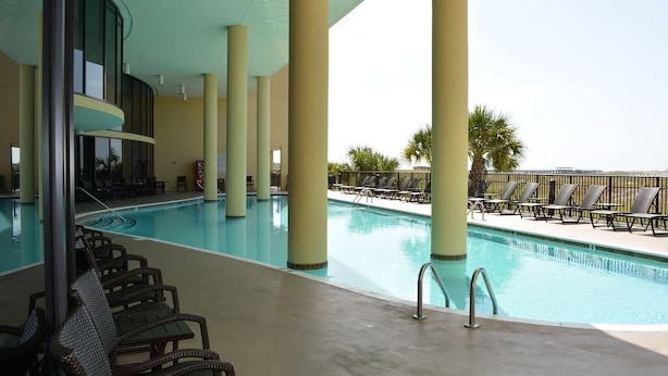Zona de piscina con sillones de descanso y vista al océano.