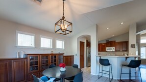 A spacious kitchen with a central island, wooden cabinets, and a dining area with chairs and a table.