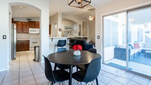 A modern kitchen with dark cabinetry, a central island, and a dining area with a round table and chairs.