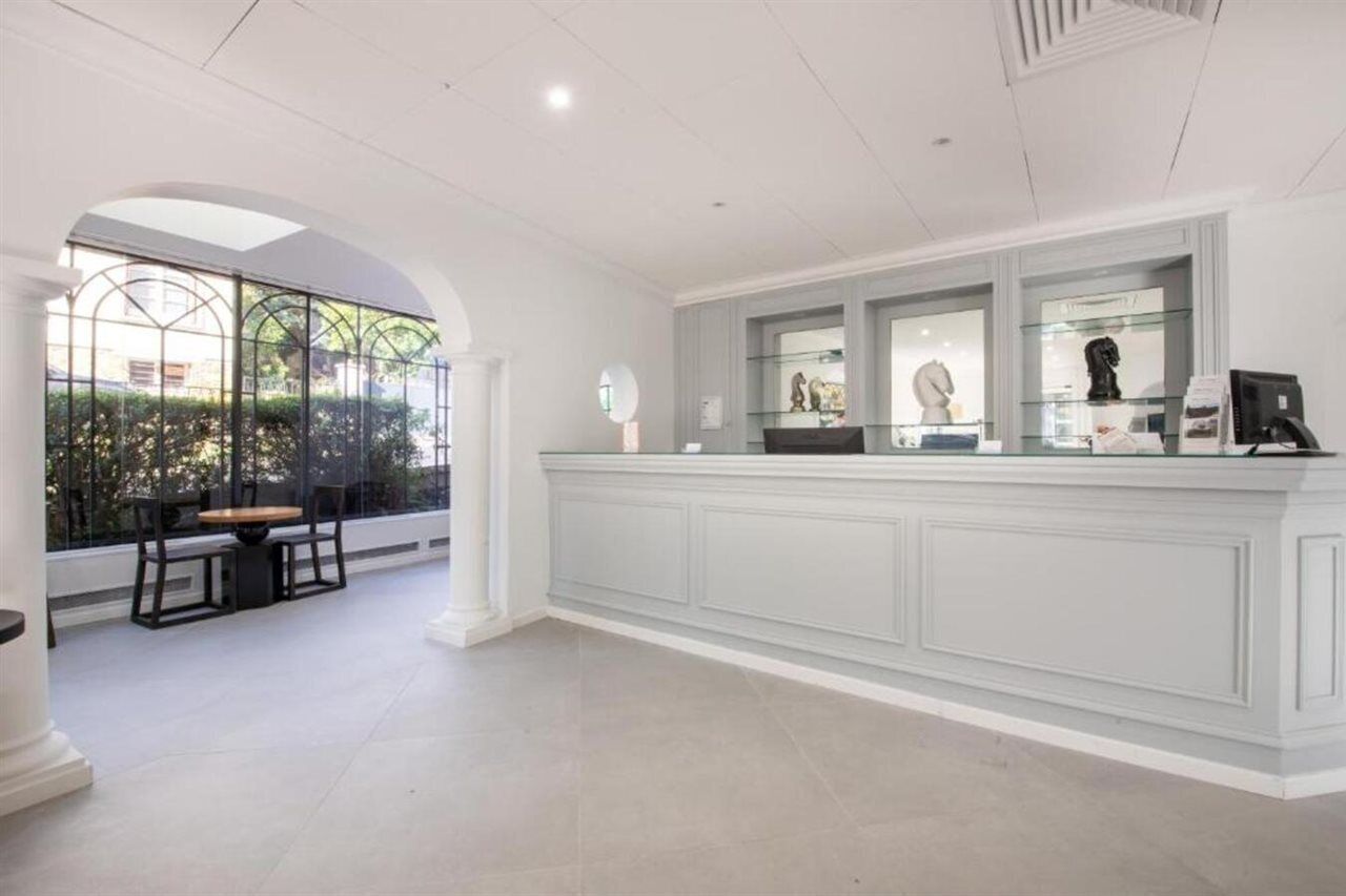 A reception area with a white reception desk, glass display cases, and a seating area with chairs and a table.
