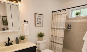 Ein Badezimmer mit Waschbecken, Spiegel, Toilette und Duschvorhang.