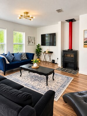 Een moderne woonkamer met een blauwe bank, een zwarte salontafel en een open haard.