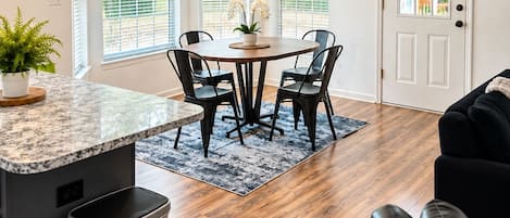 Una cocina moderna con comedor, suelo de madera y un sofá de cuero negro.