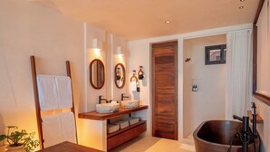 Un bagno moderno con un mobile bagno in legno, due lavabi, una vasca da bagno ampia e uno specchio.