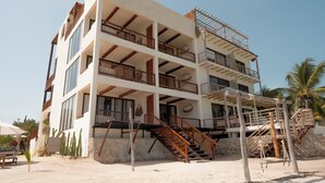 Un edificio a più piani con balconi, una scala e terreno sabbioso.