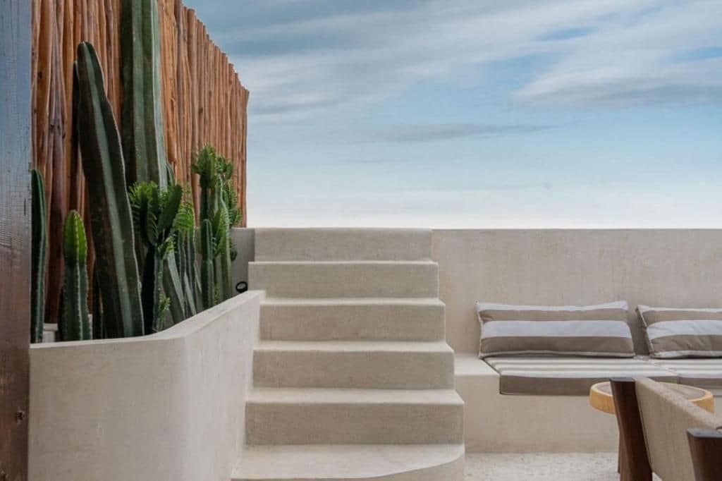 Ein moderner Balkon mit Liege, Holzlattenzaun und Kakteen.