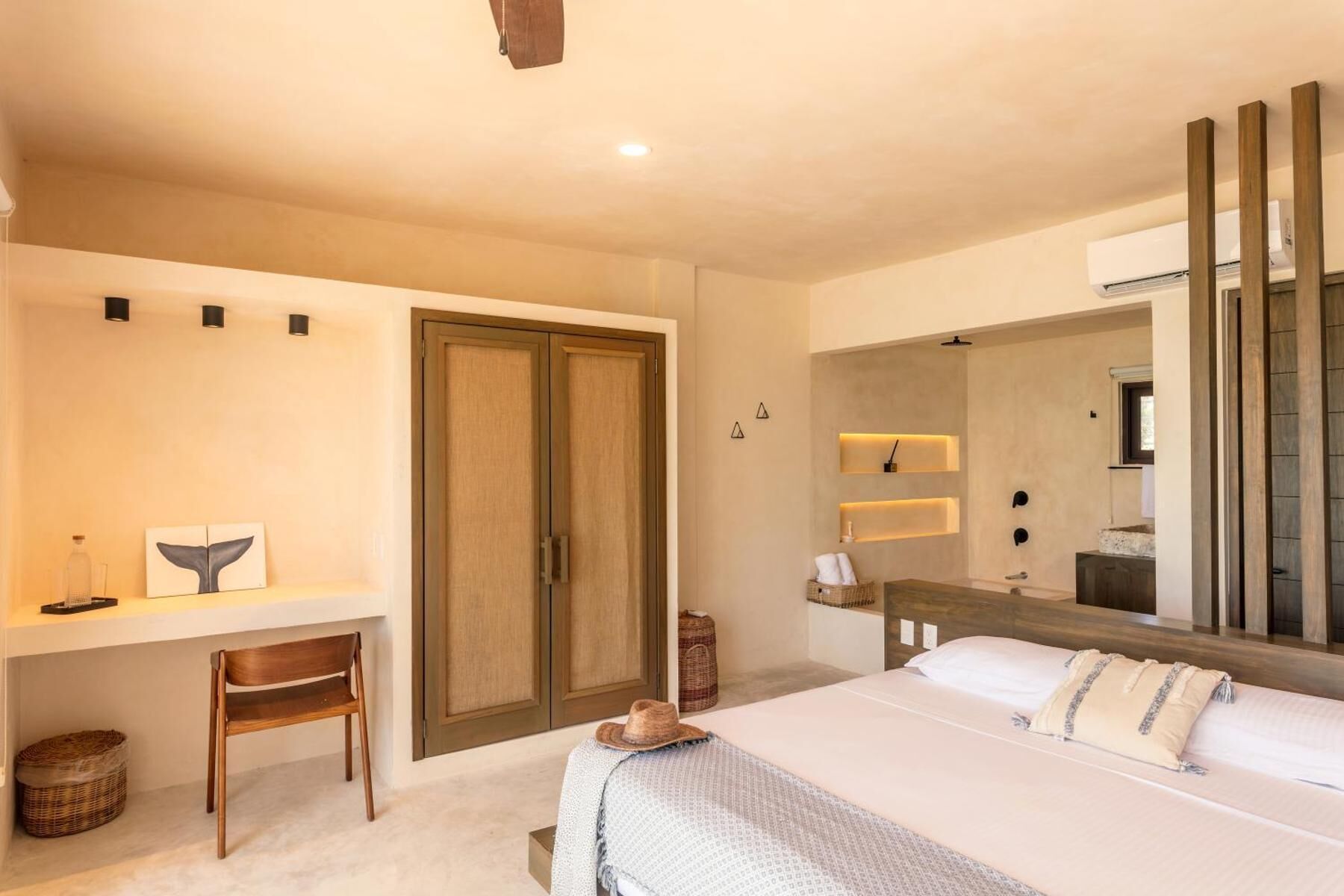 Un dormitorio con cama, escritorio, silla, armario, espejo y una mesita de noche.