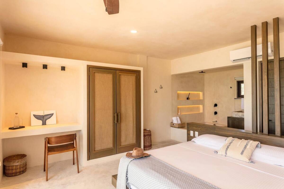 Un dormitorio con cama, escritorio, silla, armario, espejo y una mesita de noche.