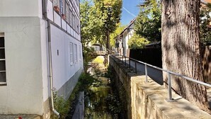 Un estrecho canal bordeado por edificios, un árbol y una barandilla de metal.