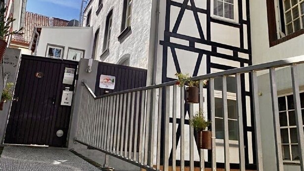 Un estrecho callejón con un edificio de entramado de madera a la vista y una reja negra.