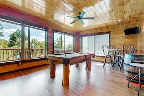 Relax in this spacious area with a pool table, comfortable seating, and a large TV.