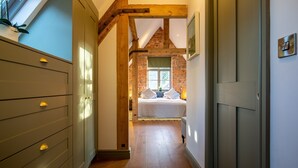 Ein schmales Gang mit einem Bett im Hintergrund, Holzbalken und einem Fenster mit Blick.