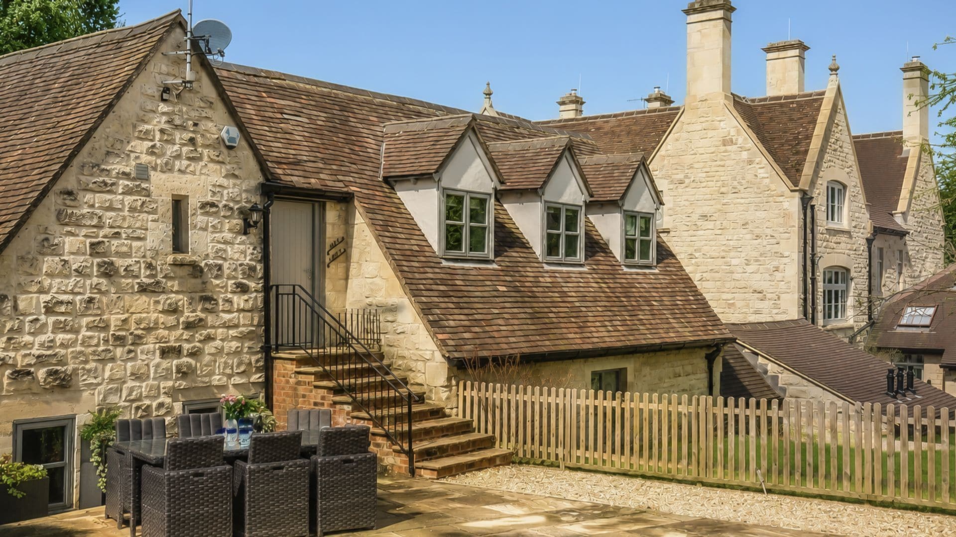 A stone building with a wooden fence, a staircase, and outdoor seating.