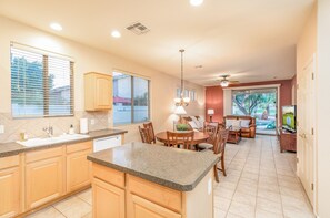 Enjoy meals and relaxation in this open-plan kitchen and dining area with a central island, round table, and comfortable seating.