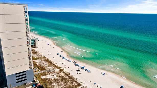 A beach with a high-rise hotel adjacent to it. - Beautiful Beachfront Condo with Amazing Views and Beachfront Pool! Chair Service Included* (Panama City Beach)