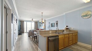 A modern kitchen with a central island, wooden cabinets, and a dishwasher. - Beautiful Beachfront Condo with Amazing Views and Beachfront Pool! Chair Service Included* (Panama City Beach)