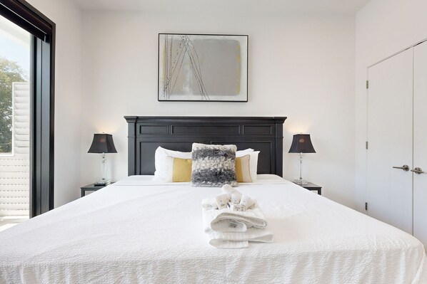 Restful retreat with a large bed, bedside lamps, and a modern art piece.