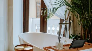 Un baño moderno con una bañera independiente, una bandeja de madera y un recipiente de vidrio con cañas negras.