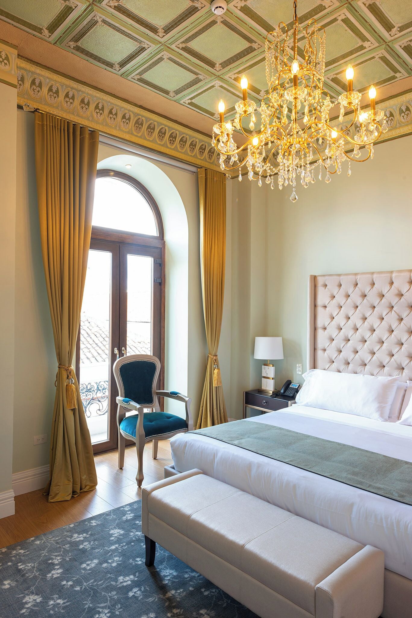 Une chambre à coucher avec un grand lit, un lustre, une chaise et une table de chevet.