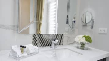 A modern bathroom with a large mirror, a sink, and a glass tray with toiletries.