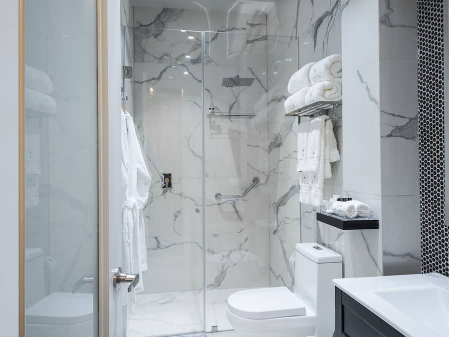 A modern bathroom with a glass-enclosed shower, a white toilet, and a vanity with a mirror.