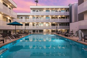 Relax by the rooftop pool surrounded by lounge chairs and umbrellas.