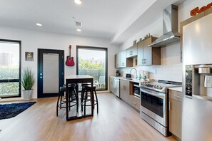 Enjoy cooking in this well-lit kitchen with a range hood, oven, and large stovetop.