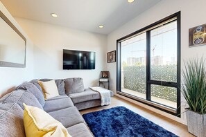 Relax in this stylish living room with a large sofa, flat-screen TV, and city views.