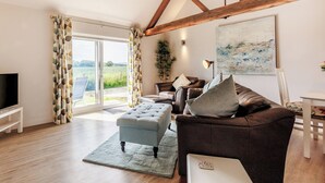 A living room with a sofa, ottoman, and a flat-screen TV. - 1 bedroom accommodation in Ocle Pychard (Ocle Pychard)