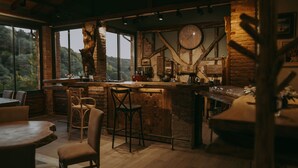 Een landelijke keuken met een groot houten eiland, stenen muren en een groot raam met uitzicht op een bos.