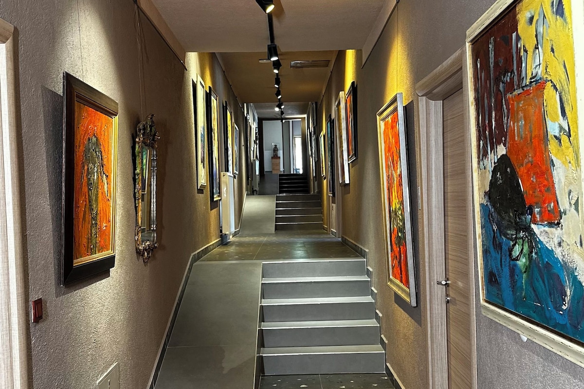 Ein Flur mit einer Treppe, Wänden, die mit gerahmten Kunstwerken geschmückt sind, und einem gefliesten Boden.
