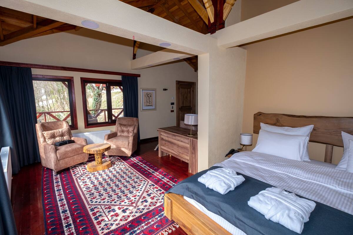 Un dormitorio con una cama de madera, una silla, un tocador y una ventana con cortinas.
