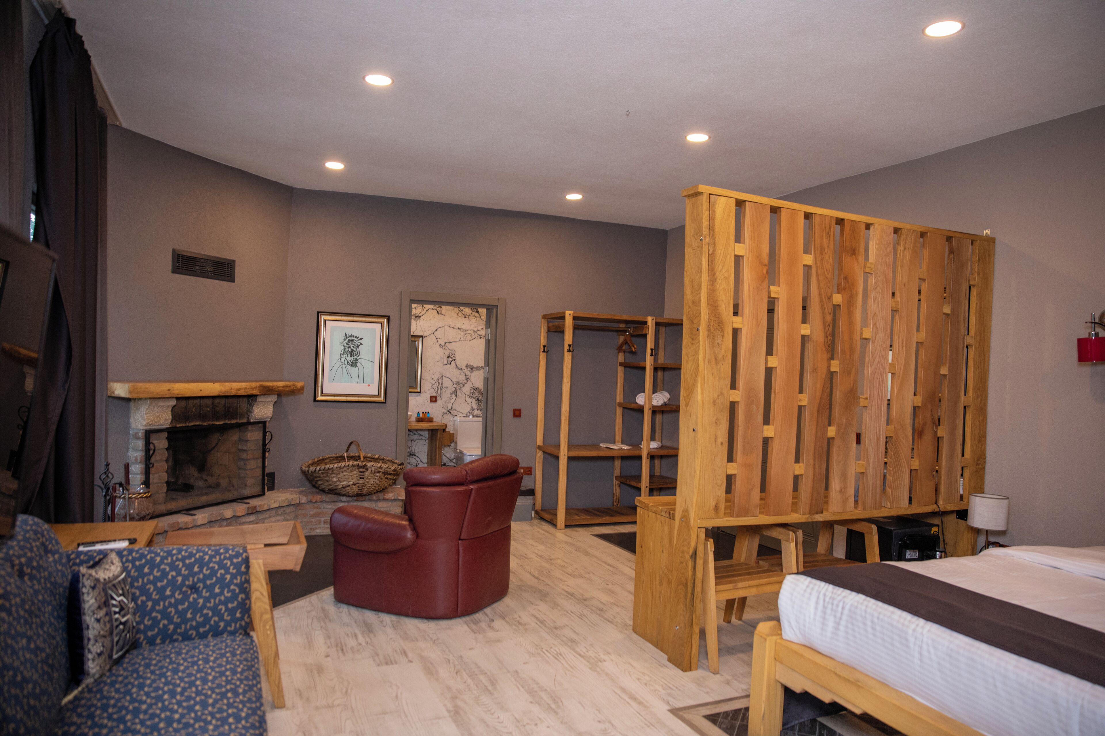 A room with a fireplace, a sofa, a chair, a bed, and a wooden partition.