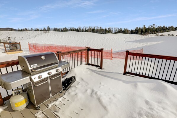 A snow-covered deck with a grill and gas tank, surrounded by a wooden fence and snowbanks. - Beautiful home in Owl’s Nest close to River/Lake (Thornton)