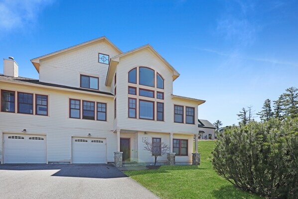 A two-story house with a garage, a front porch, and a well-maintained lawn.